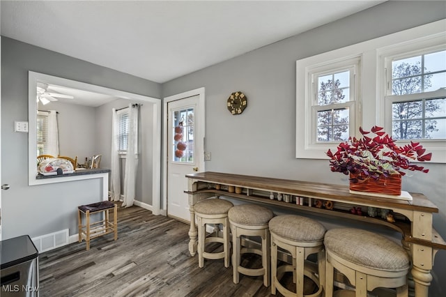 dining room with a healthy amount of sunlight, ceiling fan, and dark hardwood / wood-style flooring