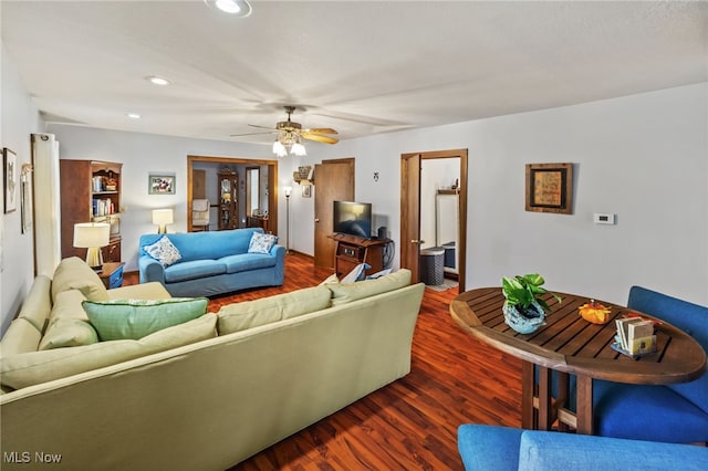 living room with ceiling fan and dark wood-type flooring