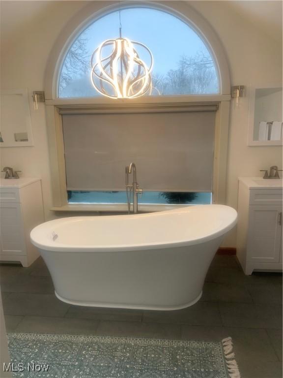 bathroom featuring vanity, tile patterned flooring, and a tub to relax in