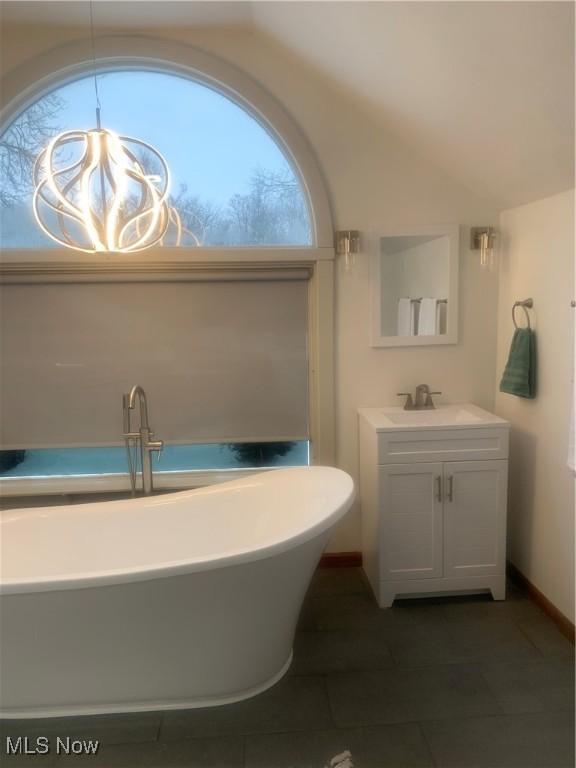 bathroom with lofted ceiling, vanity, tile patterned flooring, and a bathing tub