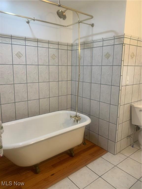 bathroom with tile patterned flooring, tile walls, and  shower combination