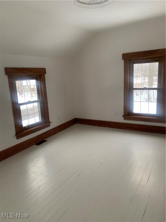 unfurnished room with a healthy amount of sunlight and vaulted ceiling