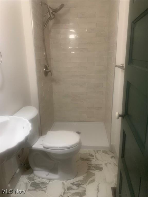 bathroom with toilet and tiled shower