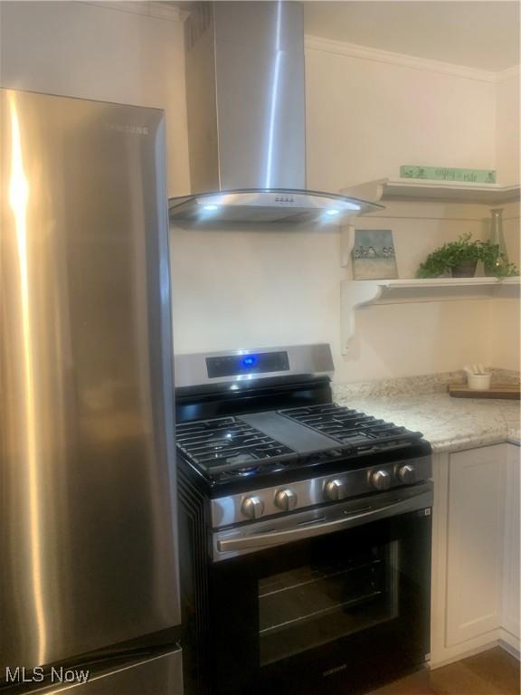 kitchen with appliances with stainless steel finishes, crown molding, light stone counters, white cabinetry, and extractor fan