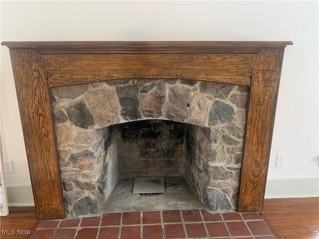 room details with a stone fireplace and wood finished floors