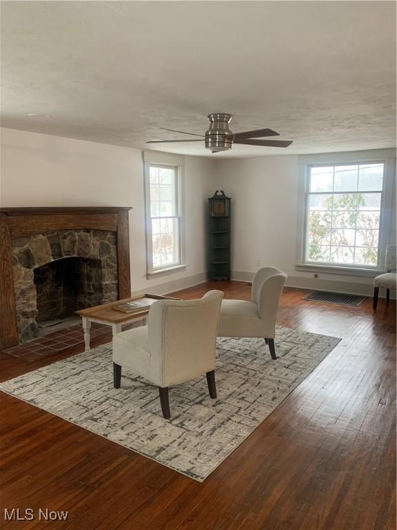 living room with ceiling fan, dark wood-type flooring, and a fireplace