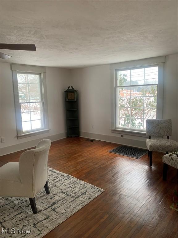 living area with ceiling fan and dark hardwood / wood-style flooring