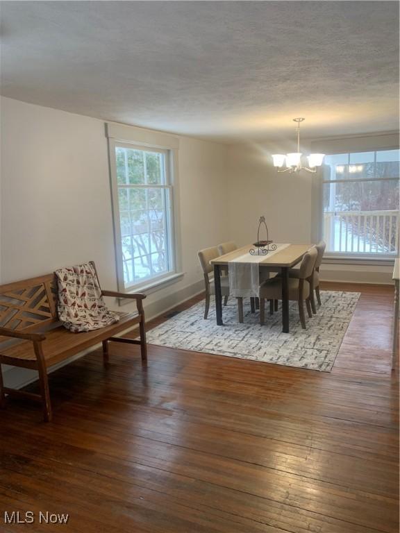 dining area with a notable chandelier and dark hardwood / wood-style flooring