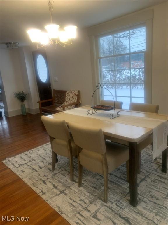 dining space featuring a notable chandelier, dark wood-type flooring, and a healthy amount of sunlight