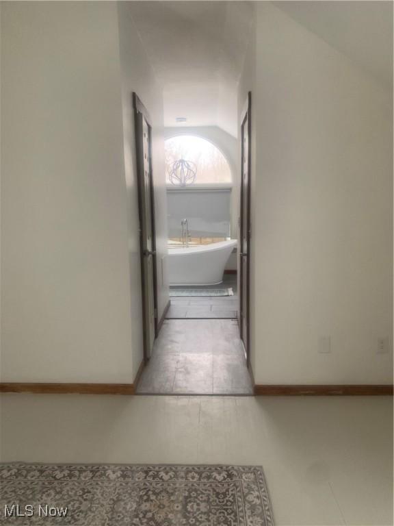 hall with lofted ceiling and light tile patterned floors