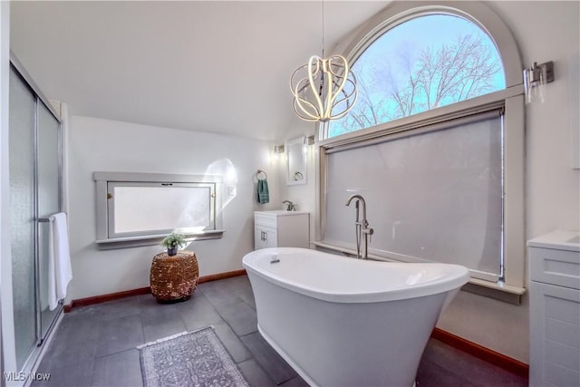 full bath featuring baseboards, a stall shower, an inviting chandelier, a soaking tub, and vanity