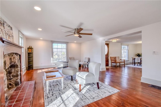 living area with a wealth of natural light, wood finished floors, ceiling fan, and a tile fireplace