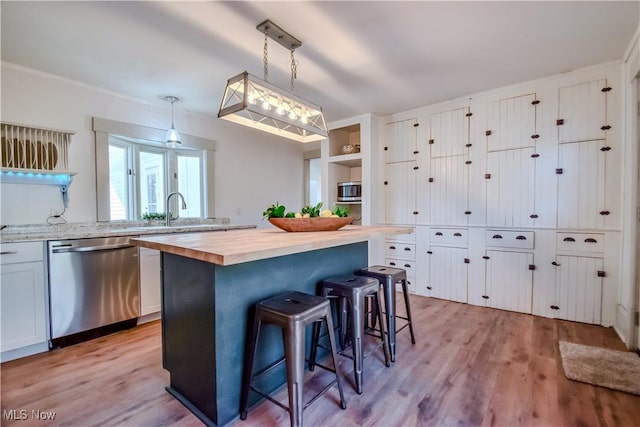 kitchen featuring a breakfast bar, light wood-style flooring, a sink, stainless steel appliances, and butcher block counters