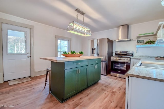 kitchen featuring open shelves, a sink, stainless steel appliances, green cabinets, and wall chimney range hood