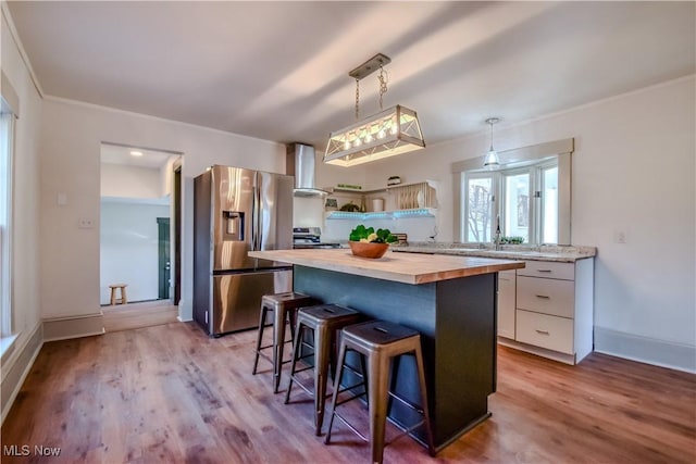 kitchen featuring a center island, butcher block countertops, a breakfast bar area, white cabinets, and stainless steel appliances