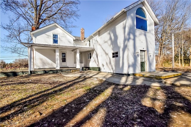 back of property featuring covered porch and a chimney