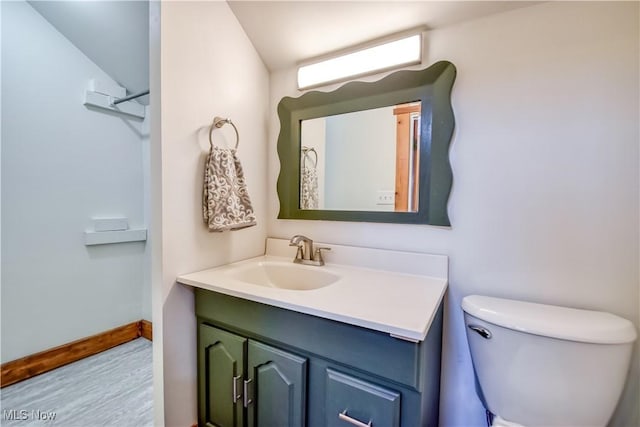 bathroom with vanity, toilet, wood finished floors, and baseboards