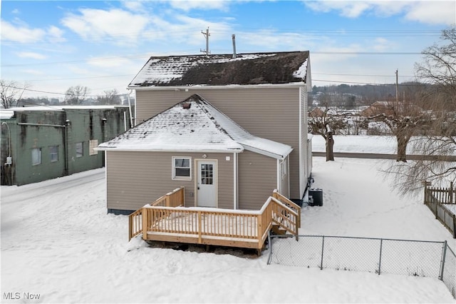 snow covered house with central AC and a wooden deck