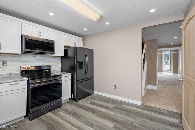 kitchen with light carpet, white cabinets, light stone counters, and stainless steel appliances