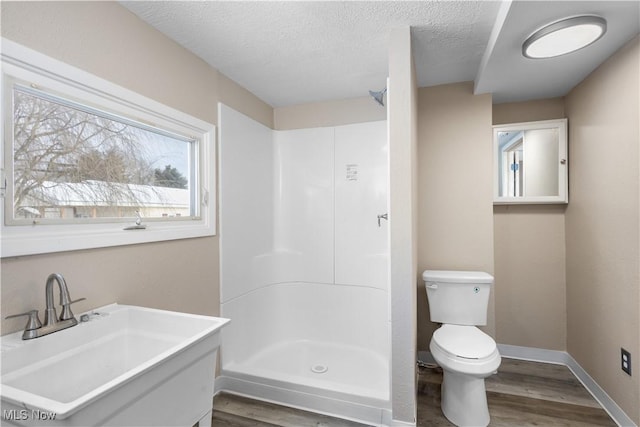 bathroom with a textured ceiling, toilet, walk in shower, and hardwood / wood-style floors