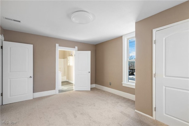 unfurnished bedroom with light colored carpet and ensuite bathroom