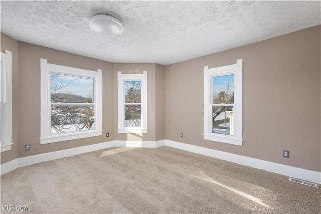 carpeted spare room with a textured ceiling