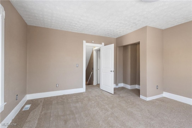 unfurnished bedroom with a textured ceiling and light carpet