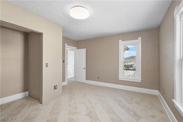 unfurnished bedroom with light carpet, a textured ceiling, and elevator