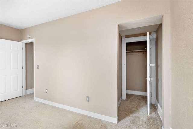 unfurnished bedroom featuring a closet and light colored carpet