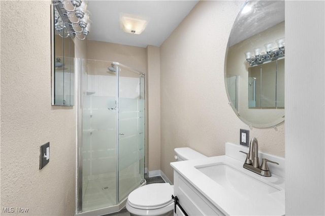 bathroom with toilet, vanity, and a shower with shower door