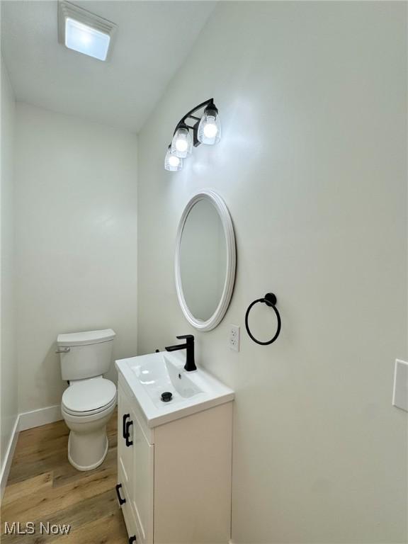 bathroom with hardwood / wood-style flooring, toilet, and vanity