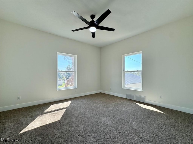 carpeted spare room featuring ceiling fan and plenty of natural light