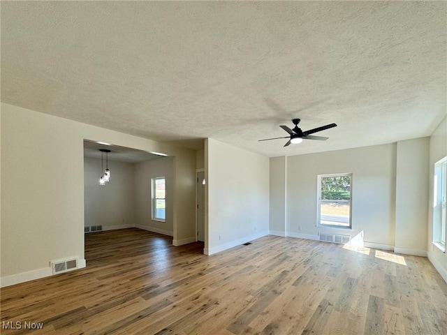 empty room with ceiling fan, wood-type flooring, and a textured ceiling