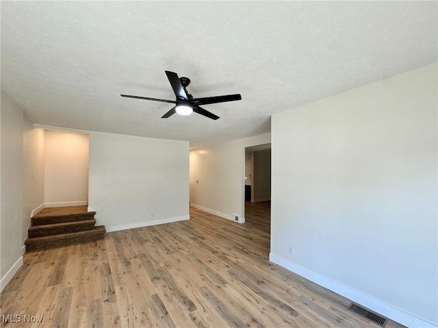 unfurnished living room with ceiling fan, a textured ceiling, and light hardwood / wood-style flooring