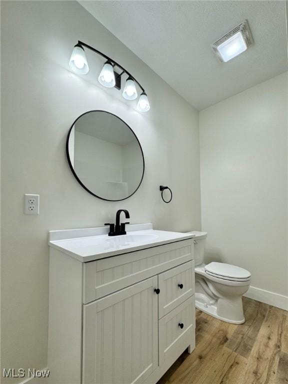 bathroom featuring toilet, hardwood / wood-style flooring, and vanity