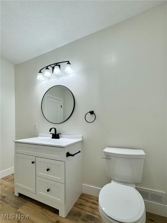 bathroom with toilet, vanity, a textured ceiling, and hardwood / wood-style flooring