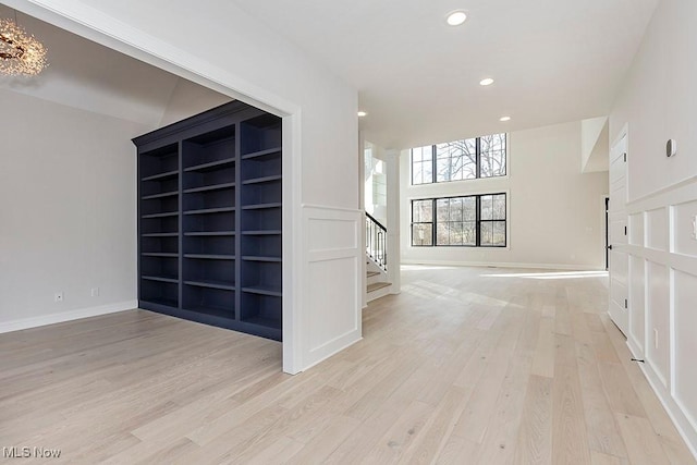 spare room featuring light wood-style floors, stairs, baseboards, and recessed lighting