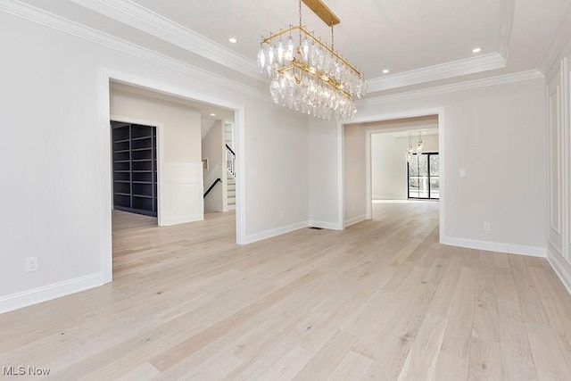 unfurnished room featuring baseboards, a notable chandelier, and light wood finished floors