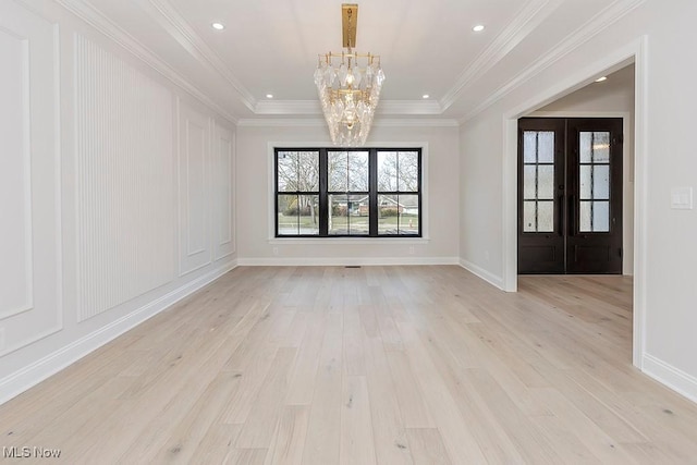 unfurnished room featuring a chandelier, light wood finished floors, and ornamental molding