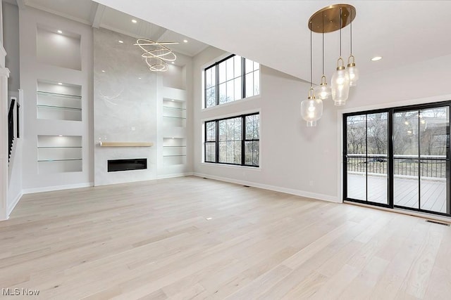 unfurnished living room with built in shelves, a fireplace, visible vents, baseboards, and light wood-style floors