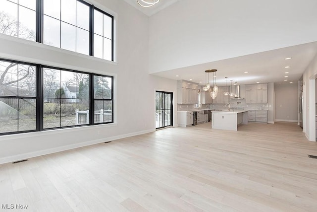 unfurnished living room with baseboards, visible vents, light wood-type flooring, a sink, and recessed lighting