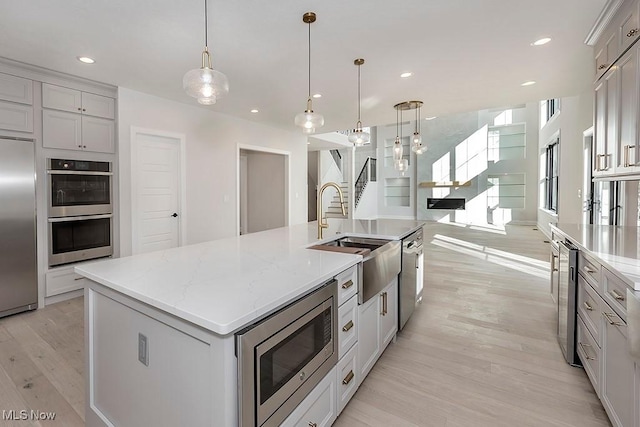 kitchen with beverage cooler, appliances with stainless steel finishes, light wood-style floors, a sink, and recessed lighting