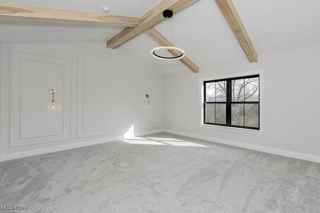 carpeted empty room with lofted ceiling with beams and baseboards