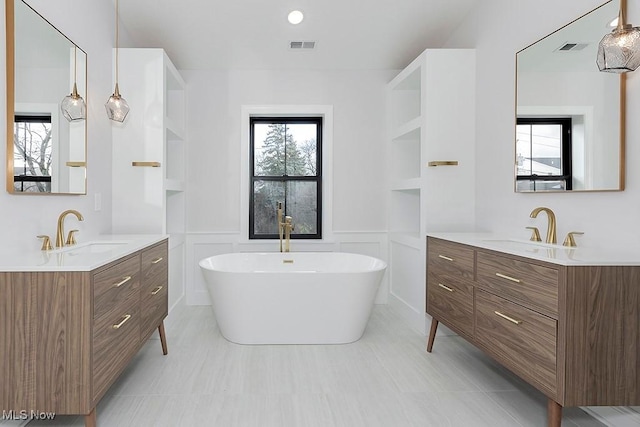 full bath featuring two vanities, a sink, and a decorative wall