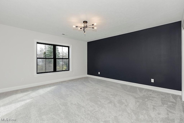 unfurnished room with carpet floors, a notable chandelier, and baseboards