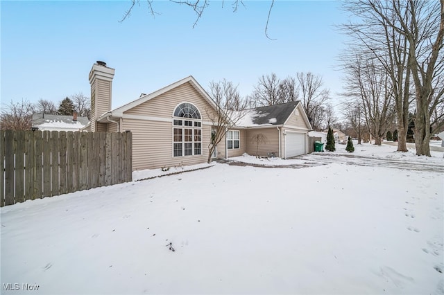 snow covered rear of property featuring a garage