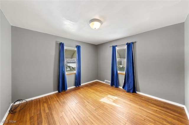 spare room featuring a healthy amount of sunlight and wood-type flooring