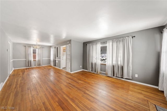 spare room featuring an inviting chandelier and wood-type flooring