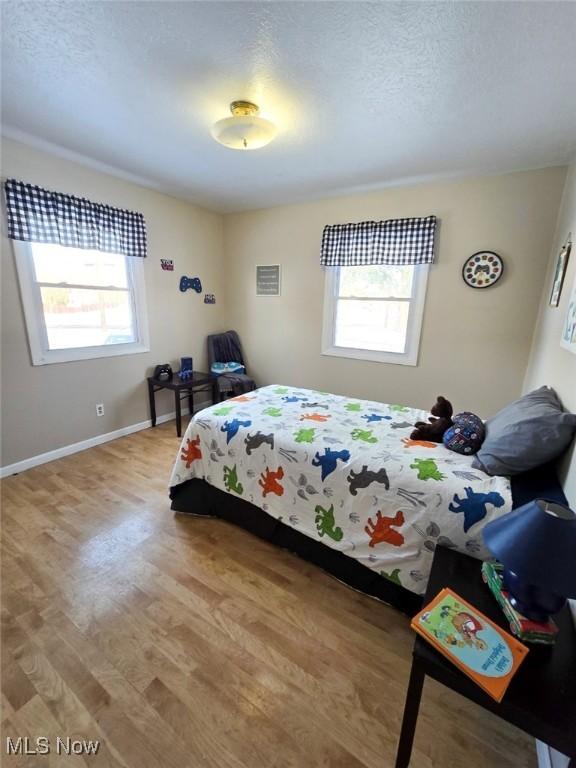 bedroom featuring hardwood / wood-style floors, multiple windows, and a textured ceiling