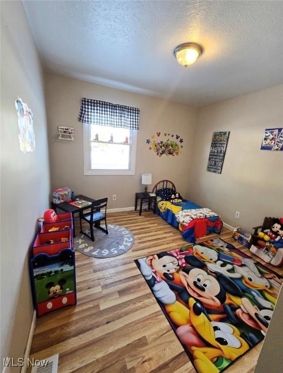 bedroom with hardwood / wood-style floors and a textured ceiling